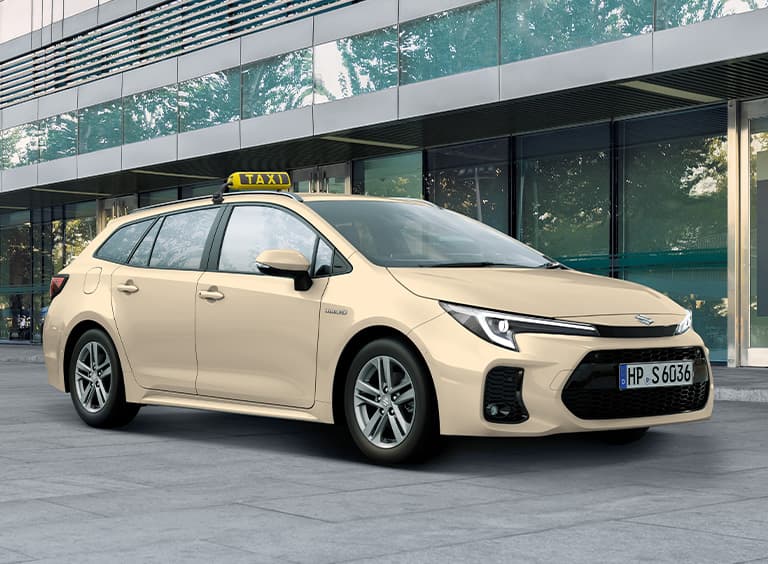 Ein Suzuki Swace in typischer Taxi-Optik mit hellgelber Lackierung und mit Taxi-Schild wartet vor einem Gebäude