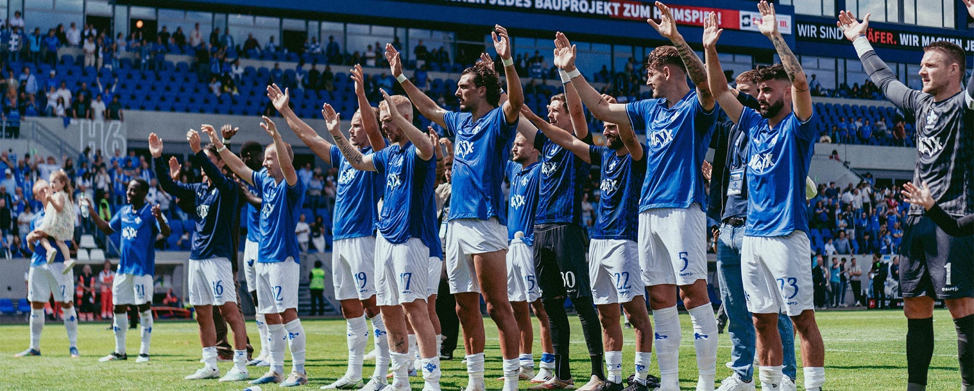 Drei Spieler von SV Darmstadt 98 bejubeln ein vor der Fantribüne