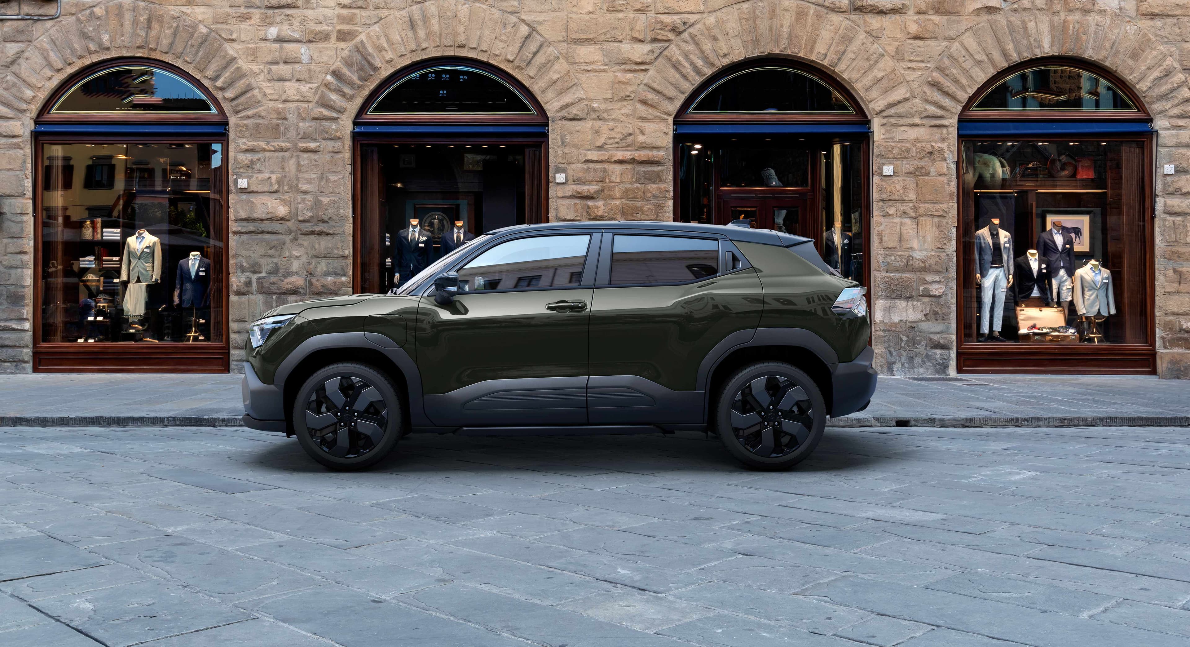 Dunkelgrüner e VITARA steht auf der Straße vor einem Haus.