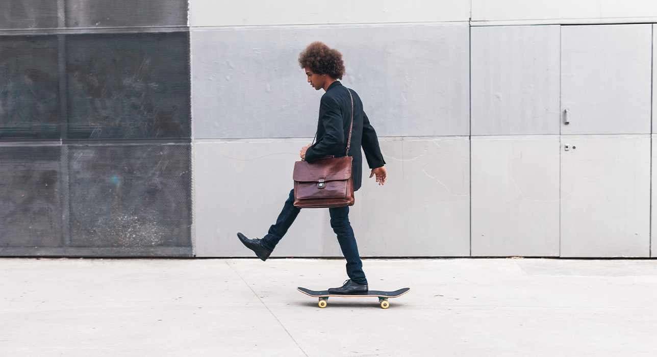 Mann mit Aktentasche fährt auf Skateboard