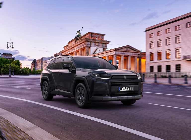 Ein dunkelgrauer Across fährt dynamisch auf einer Straße durch eine Stadt
