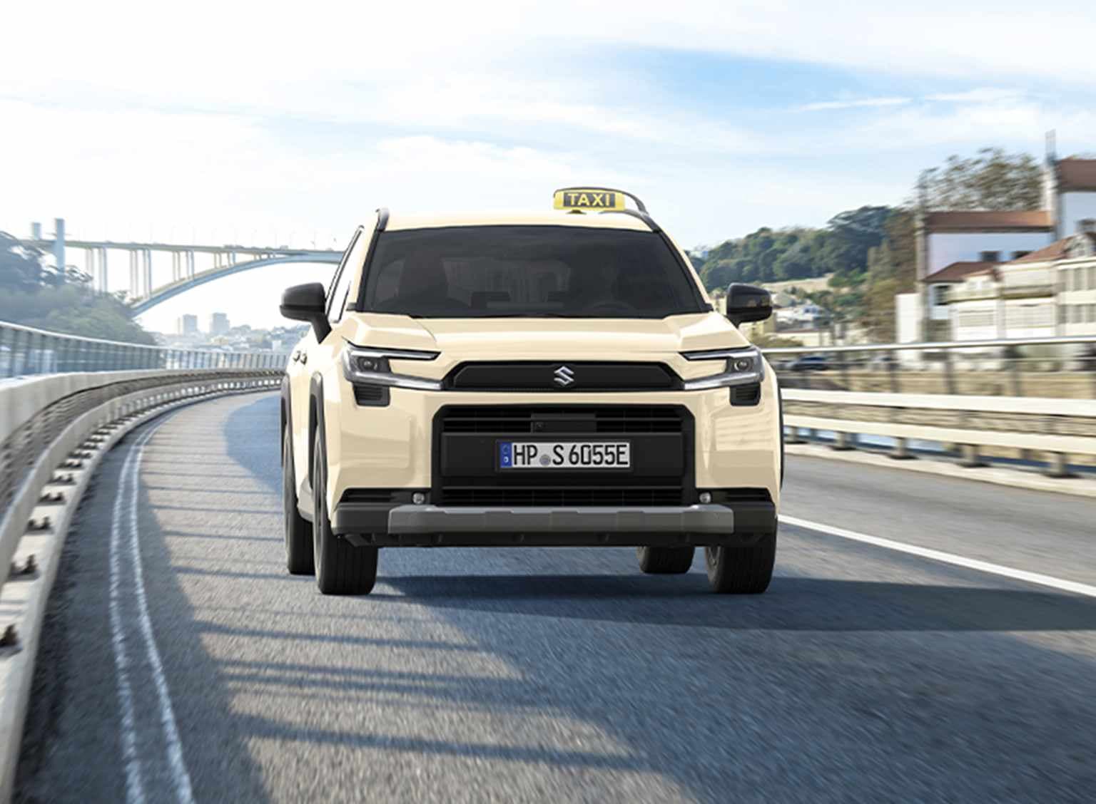 Ein Suzuki cross in typischer Taxi-Optik mit hellgelber Lackierung und mit Taxi-Schild fährt über eine Straße