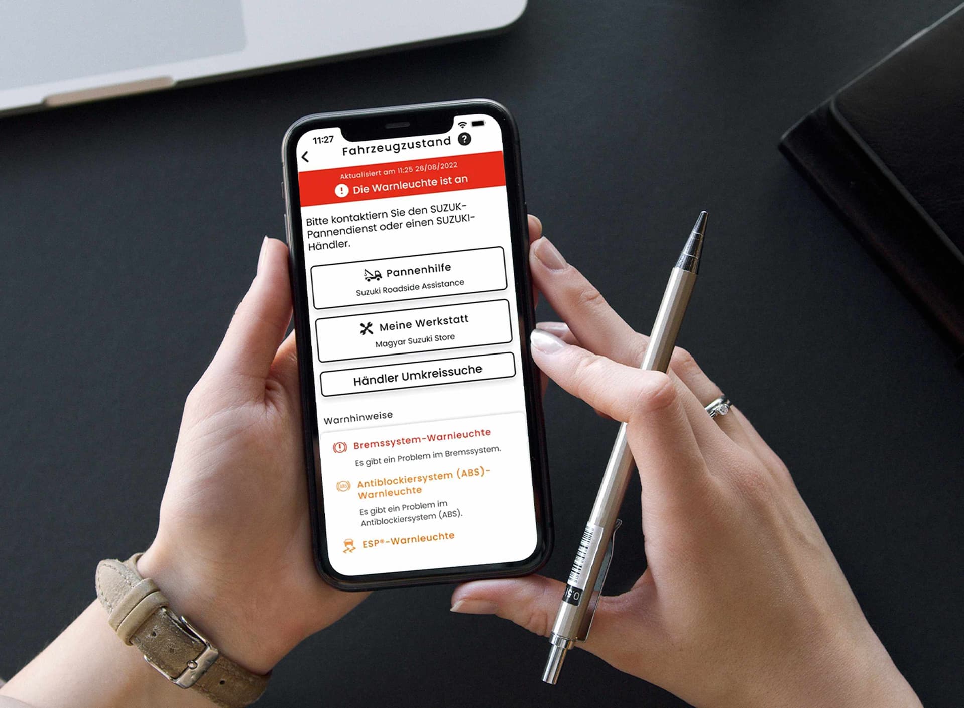 Frau hält ein Smartphone und einen Stift in der hand und auf dem Screen sind Informationen zum Fahrzeugstand