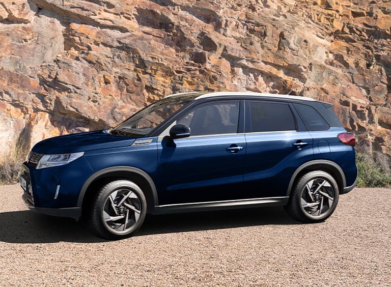 Seitenansicht eines dunkelblauen Suzuki Vitara vor einer Felswand