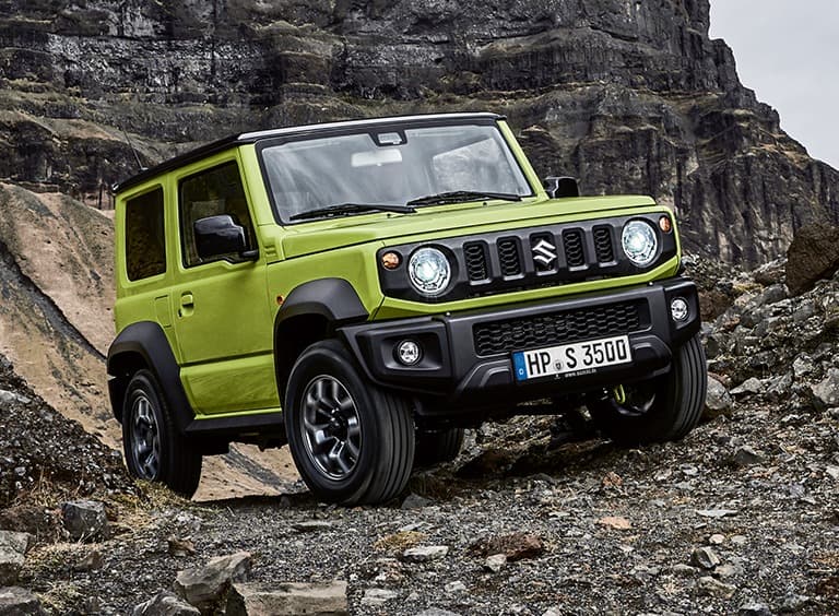 Abbildung zeigt einen grünen Jimny, der einen steinigen Hand hinauf fährt