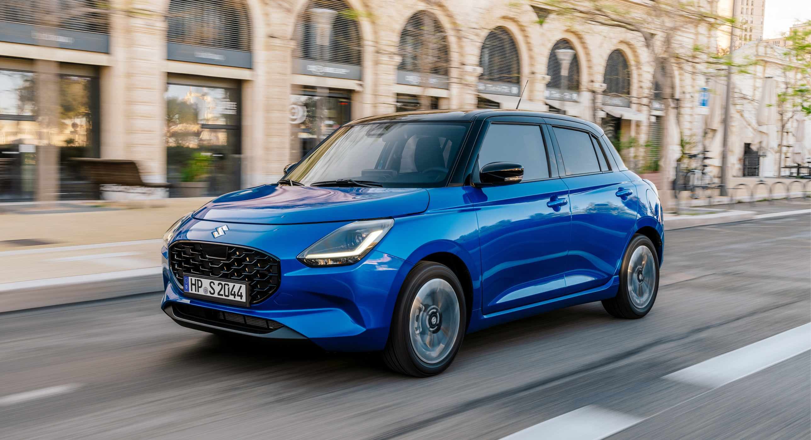 Suzuki Swift Hybrid vor lila Farbeffekt – Suzuki Deals, Verbrauch 4,4 l/100 km, CO₂-Emission 99 g/km, Klasse C