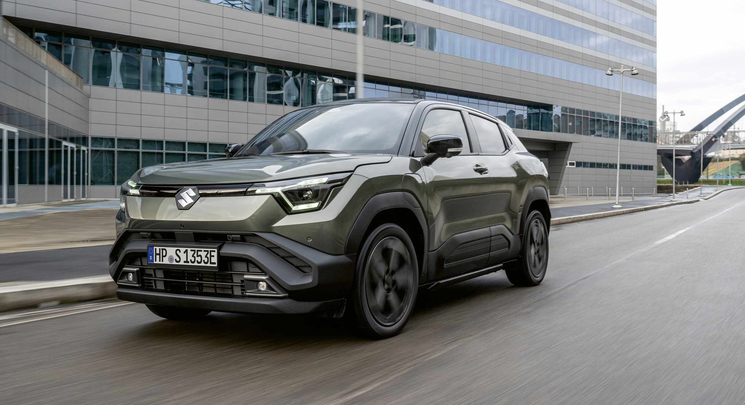 Abbildung zeigt dunkelgrünen e VITARA auf einer Straße in einer Innenstatdt