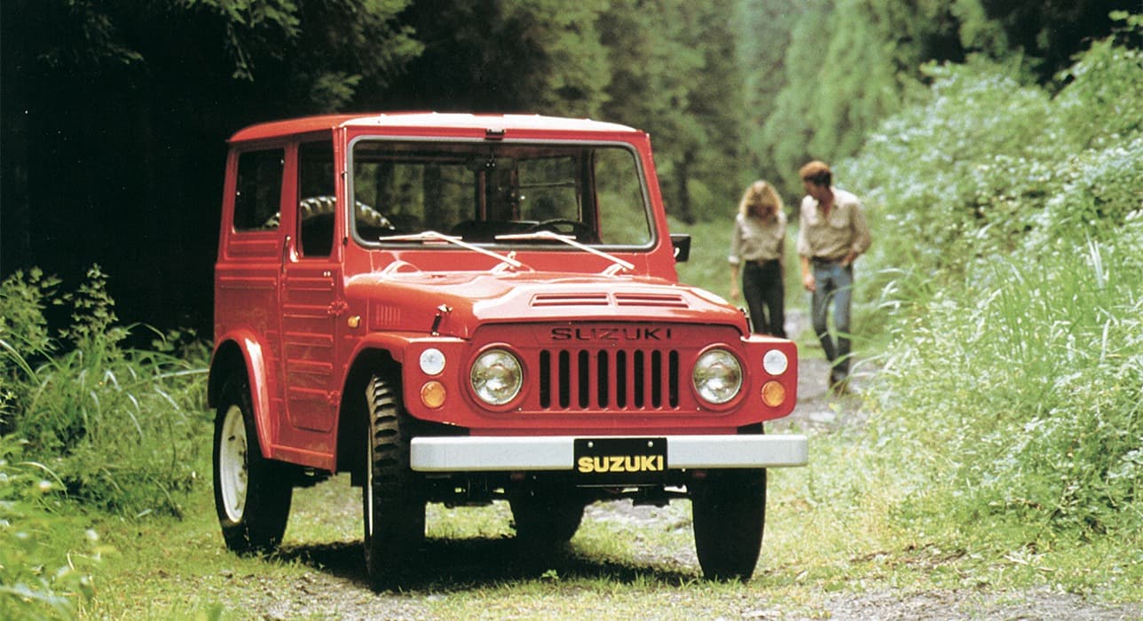 Abbildung zeigt einen roten Jimny parkend auf einem Waldweg