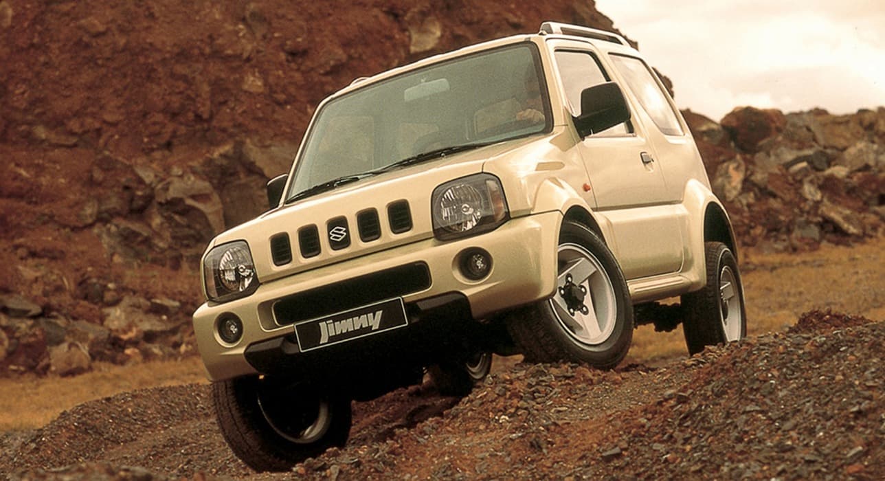 Abbildung zeigt einen weißen Jimny, der einen steilen Hang hinunter fährt