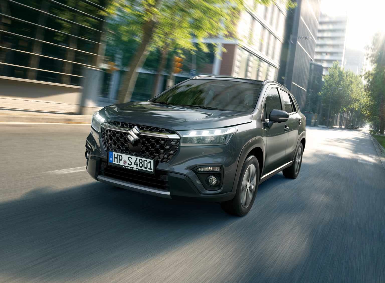 Abbildung zeigt einen grauen S-Croos auf einer Straße in einer Innenstadt