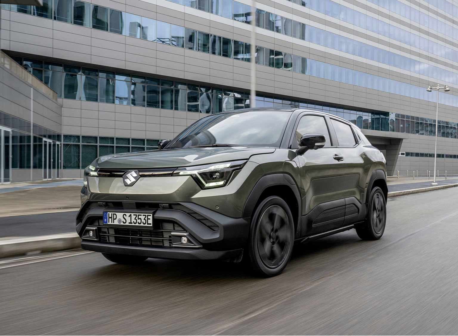 Abbildung zeigt dunkelgrünen e VITARA auf einer Straße in einer Innenstatdt