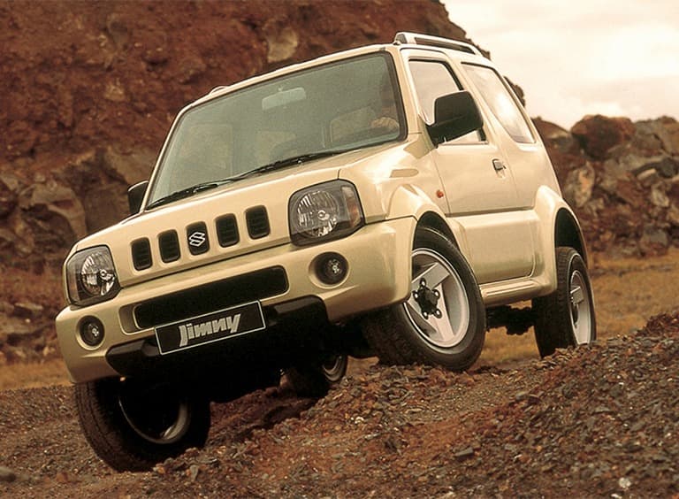 Abbildung zeigt einen weißen Jimny, der einen steilen Hang hinunter fährt