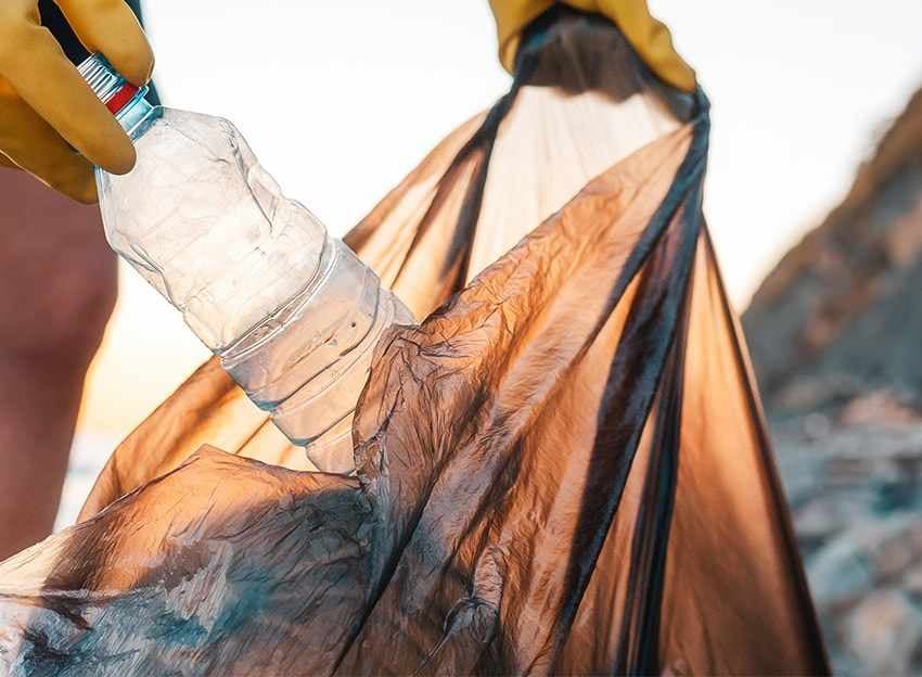 Plastikflasche wird in Müllsack gesteckt