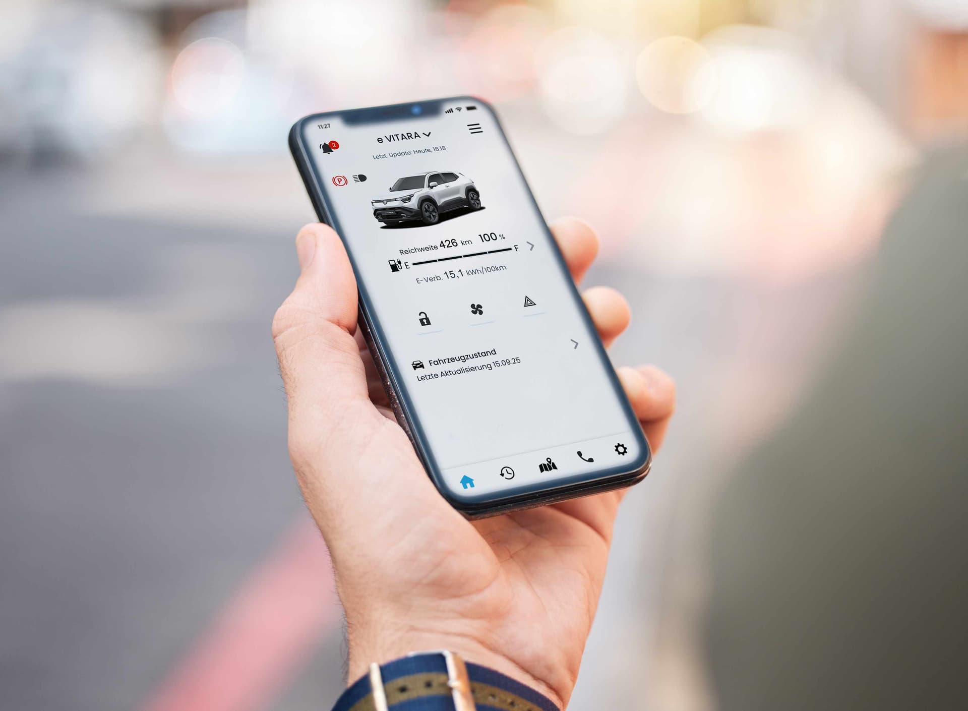 Eine Hand hält ein Smartphone und auf dem Display ist ein weißer Suzuki S-Cross zu sehen
