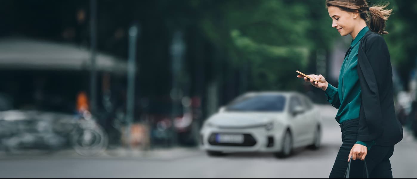 Abbildung zeigt Frau mit Handy, die Straße überquert