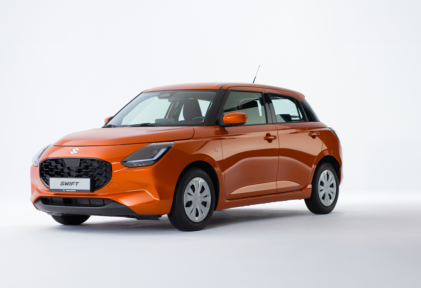 Der Suzuki Swift in orange von schräg vorne vor einem neutralen weißen Hintergrund.