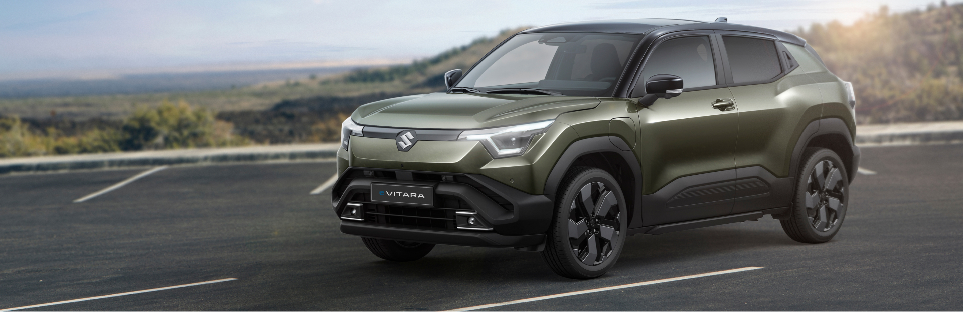 Grüner Suzuki e Vitara steht auf steinigem Boden in natürlicher Umgebung