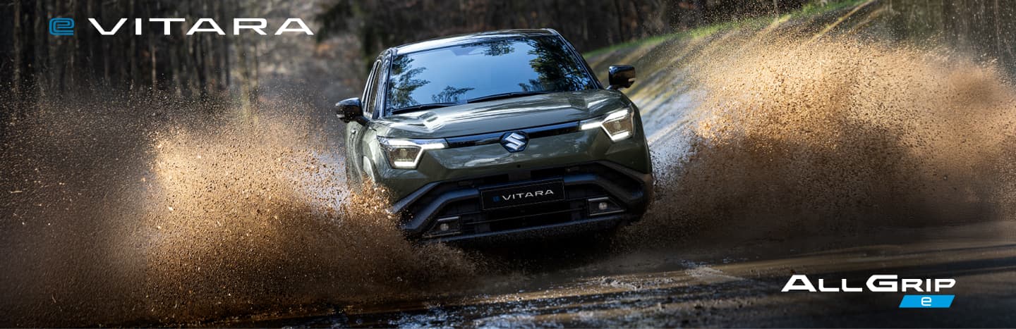 Grüner Suzuki e VITARA fährt durch eine Wasserpfütze