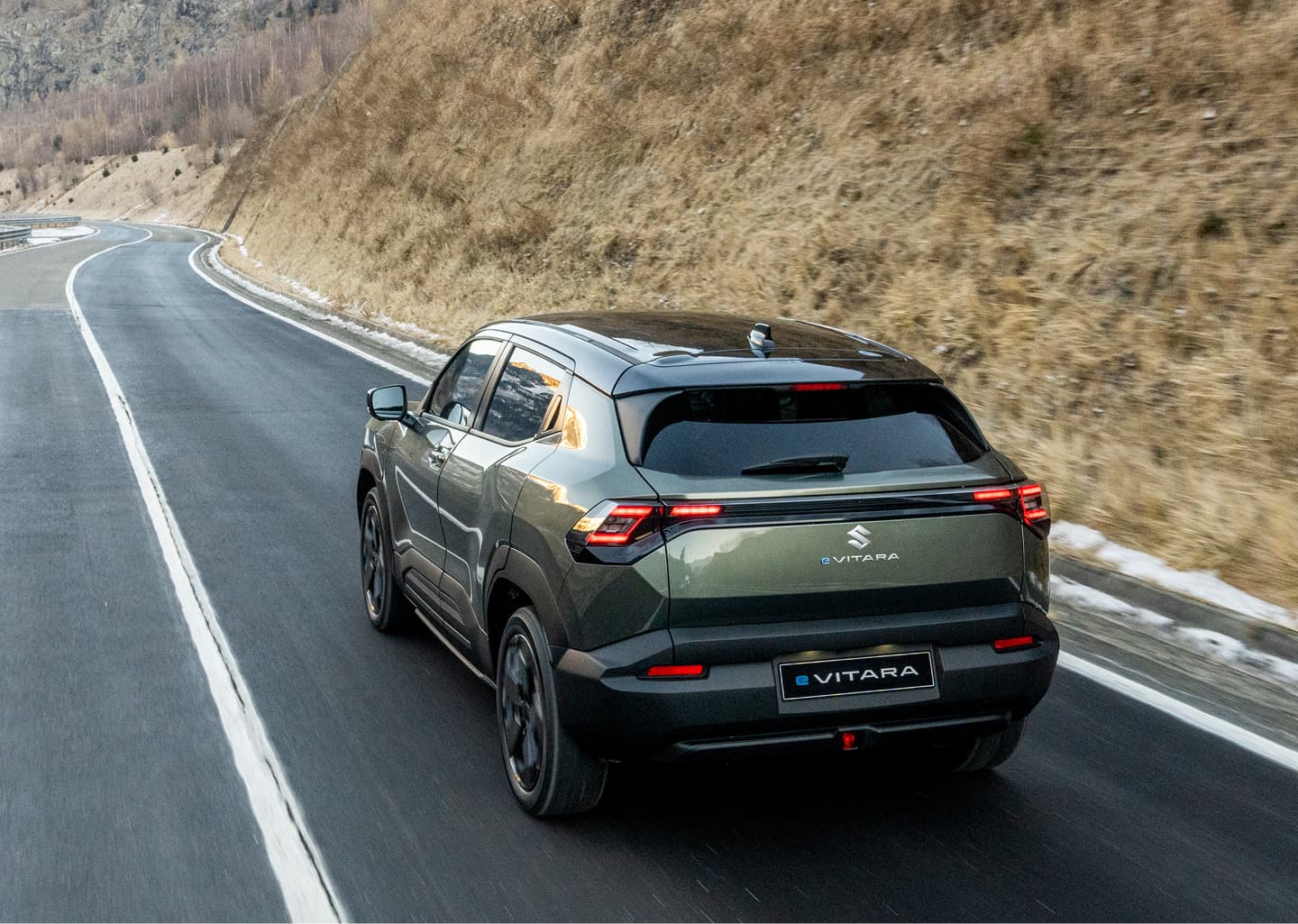 Der e VITARA in dunkelgrün fährt über eine Landstraße