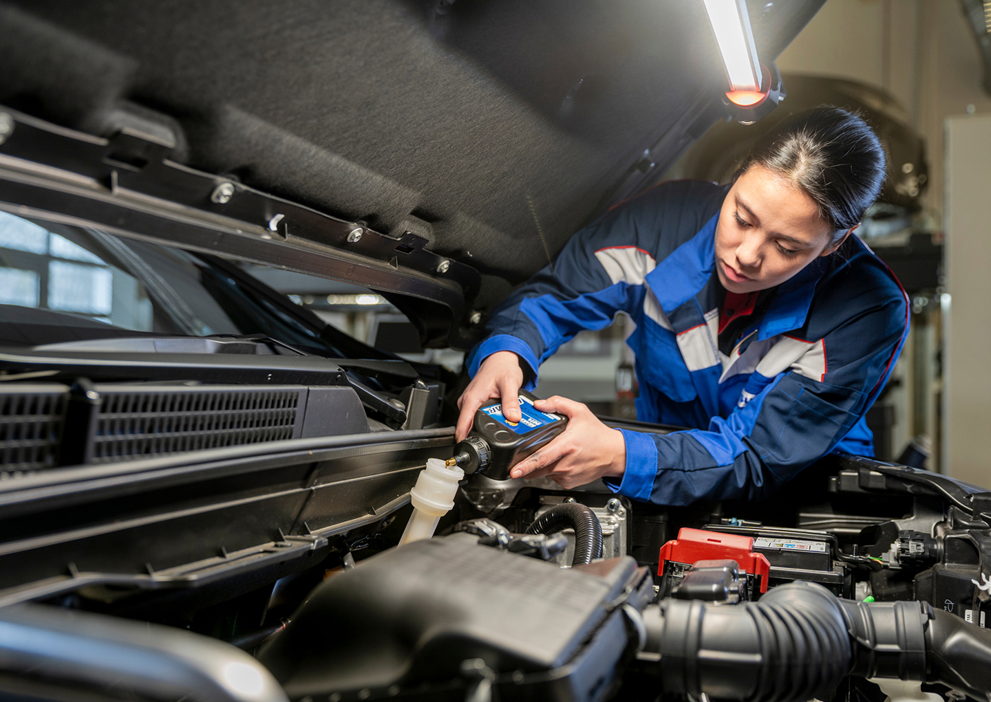 Eine Suzuki Mechanikerin füllt Öl nach